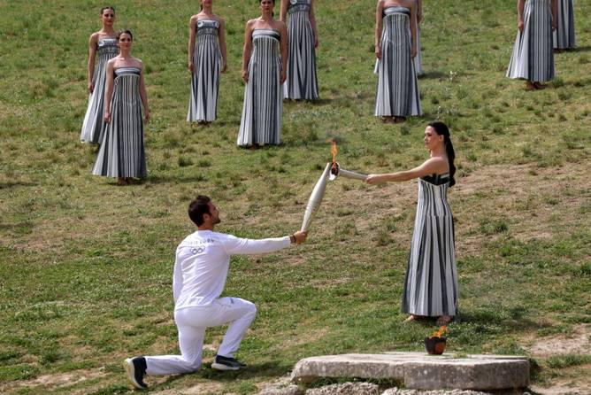 An actress lighting the torch of the first Olympic torch bearer during a ceremony in Greece