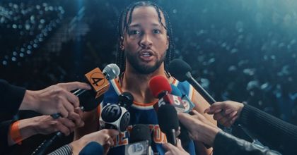 Jalen Brunson of the New York Knicks standing and speaking in front of a bunch of media people holding up microphones to his face