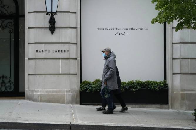 A couple walk past a boarded up Ralph Lauren store on Madison Avenue in ...