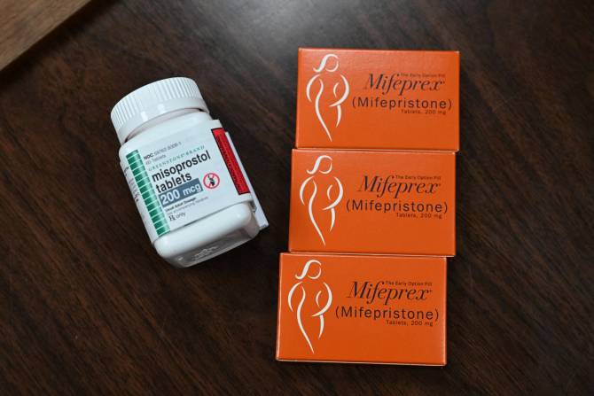 A photo of a white pill bottle and three orange boxes that hold abortion drugs.