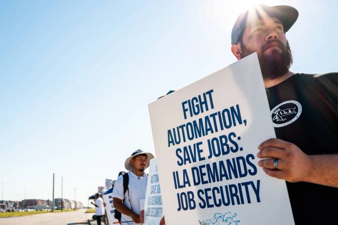 a protester in the foreground holds a sign with other protesters behind him