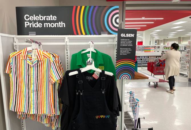 Collared shirts hang under a sign that reads "celebrate Pride month."