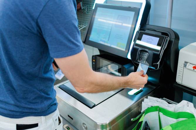 A man makes a purchase at a self-checkout machine. 