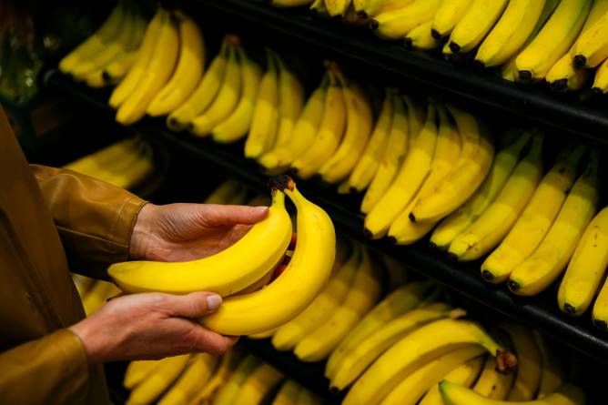 Person holding bananas at grocery store.