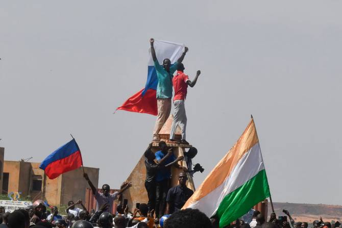 Protesters wave Nigerien and Russian flags as they gather during a rally in support of Niger's junta in Niamey on July 30, 2023. 