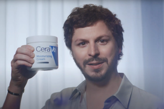 Michael Cera holds up a container of CeraVe lotion 