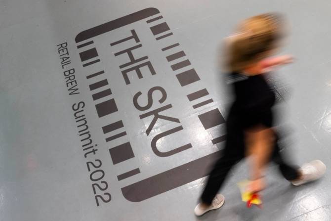 A person walks across a floor emblazoned with the logo of Retail Brew's The SKU