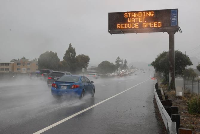 A sign in California reads "standing water, reduce speed" amid deluge