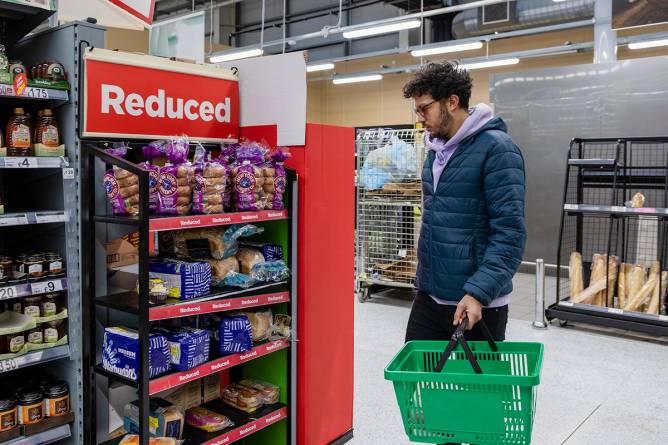 Consumer looking at reduced section in grocery store.