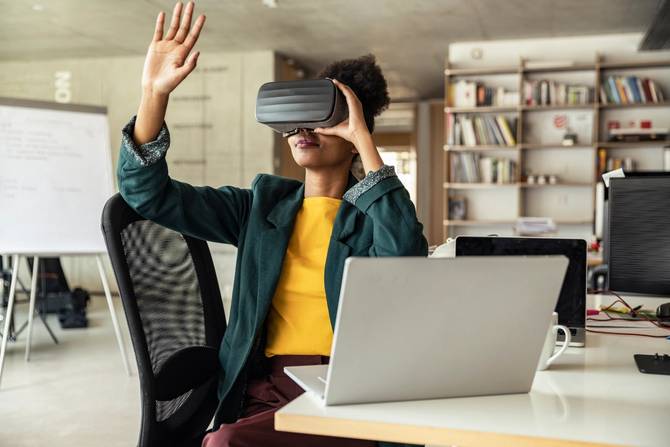 A person at a desk wears VR goggles