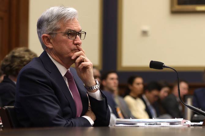 Jerome Powell sitting at a desk looking concerned 