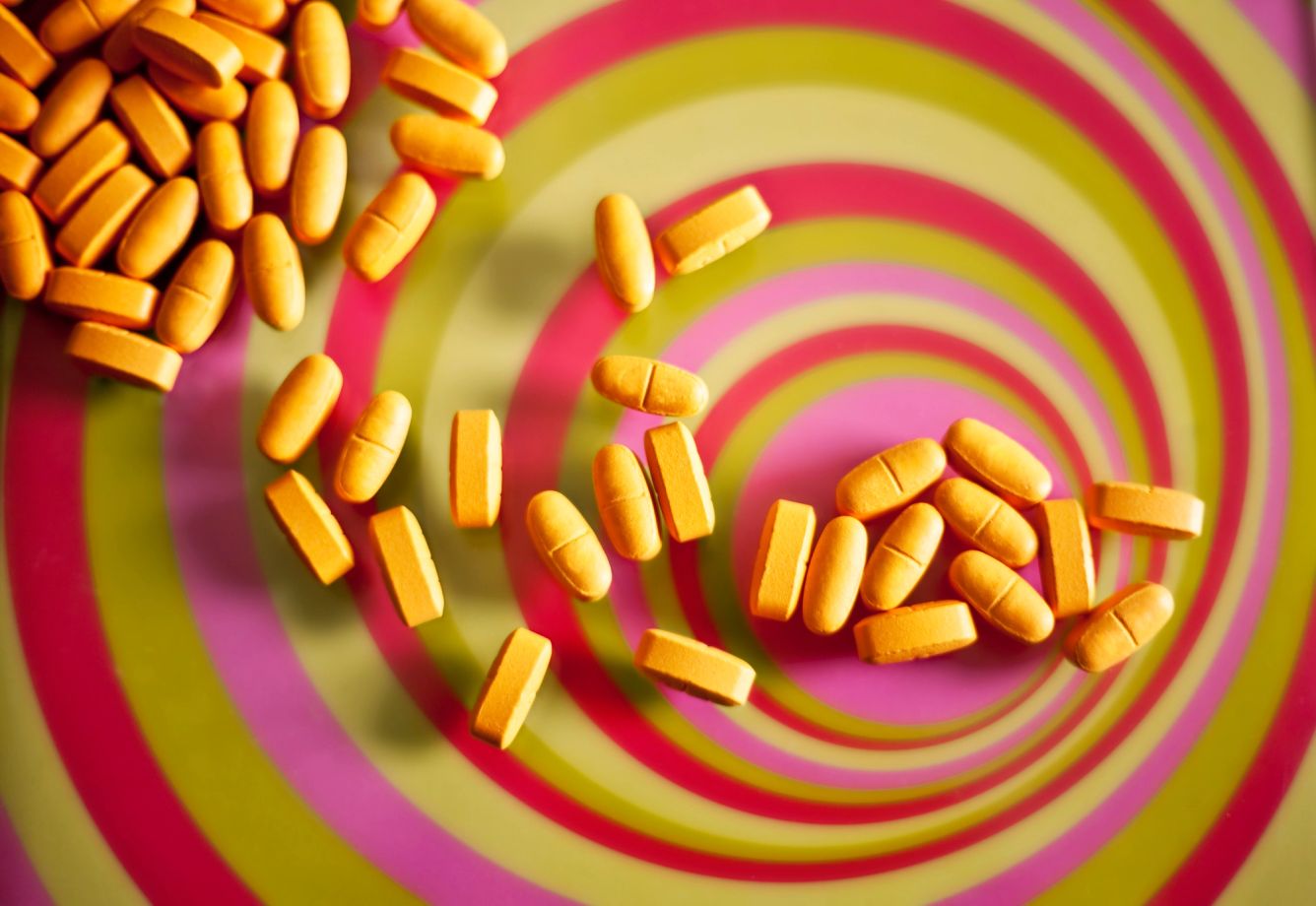 Pills falling into a swirl of color