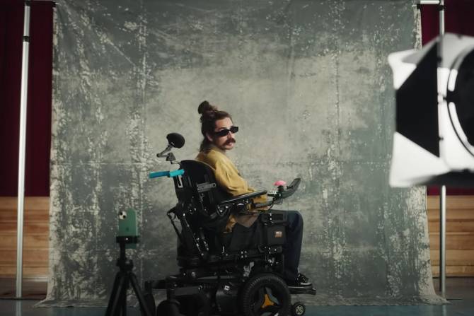 an image from an Apple ad showing a man in sunglasses in a wheelchair looking at a camera as part of a photoshoot 