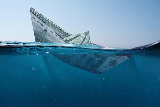 A paper boat made of $100 bills sinking