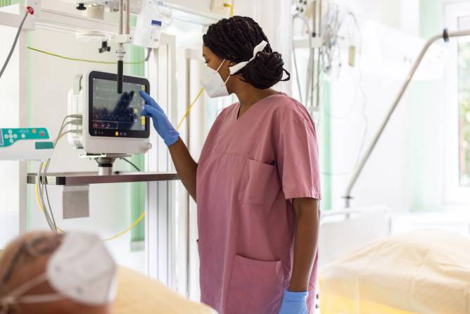 A Black nurse works in an ICU