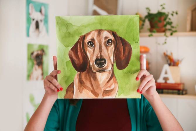 artist holding a portrait of a dog