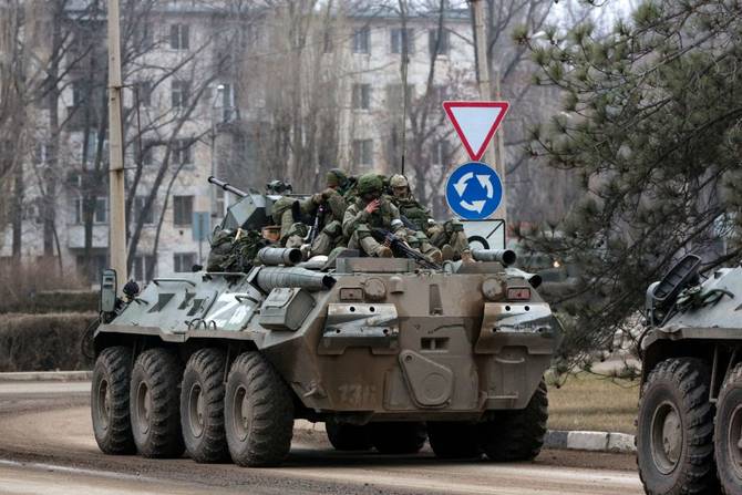 Servicemen ride atop a Russian armored vehicle in Armyansk, Crimea, on February 25, 2022