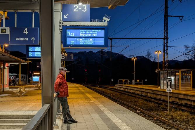 man waiting on an empty platform at night for a train