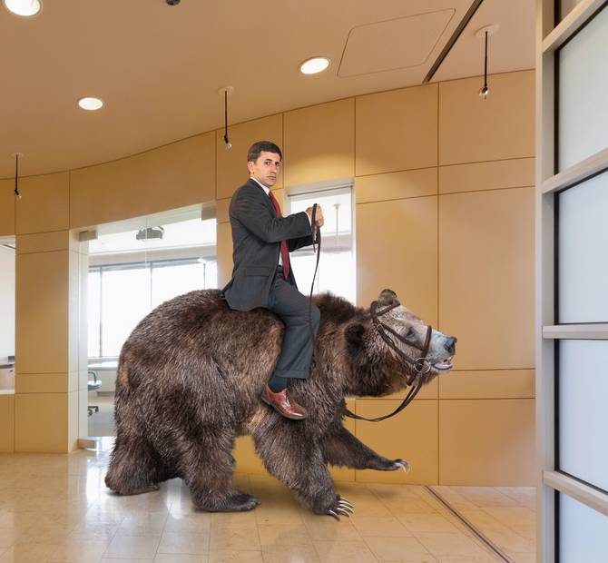 A business man riding a bear in an office. 