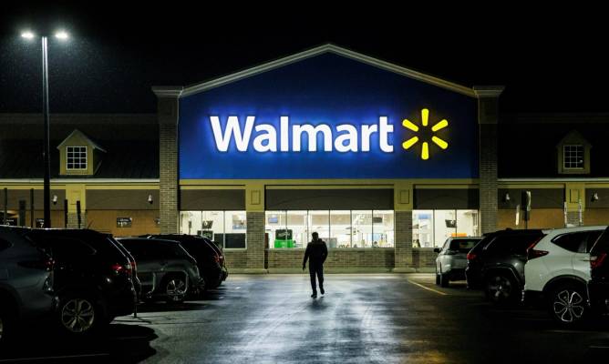 A Walmart store is visible from the parking lot in the evening.