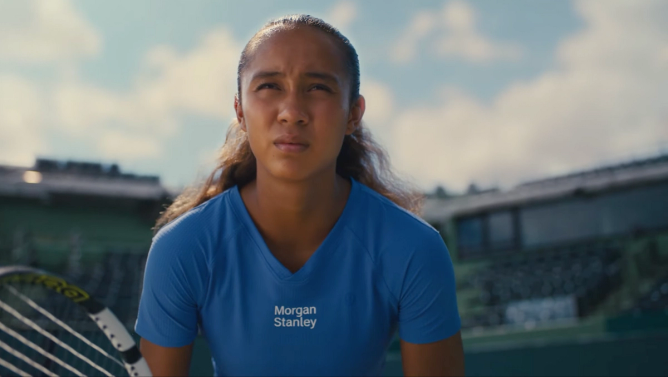 tennis player Leylah Fernandez holding a tennis racket wearing a blue shirt that reads "Morgan Stanley" in white letters