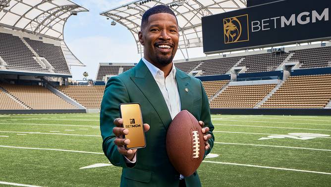 Jamie Foxx holding up a mobile phone inside of a football stadium in a BetMGM commercial