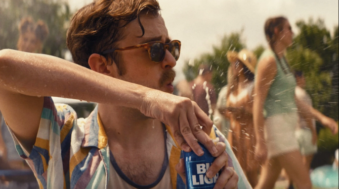 A man wearing sunglasses with a mustache in a striped shirt cracking open a can of Bud Light from the beer brand's 2023 summer ad campaign