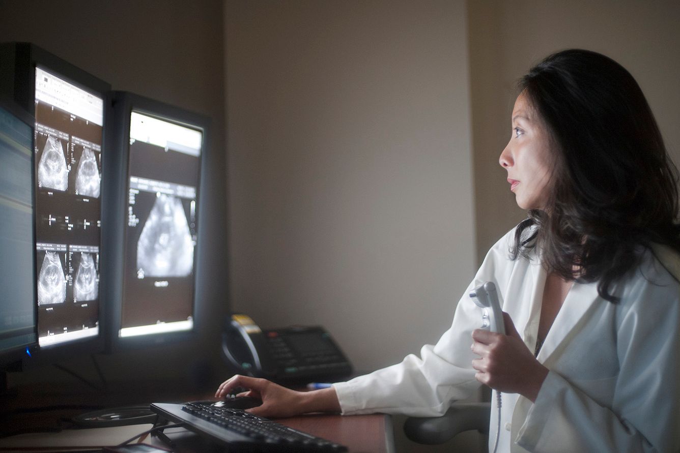 Female technician examining diagnostic image.