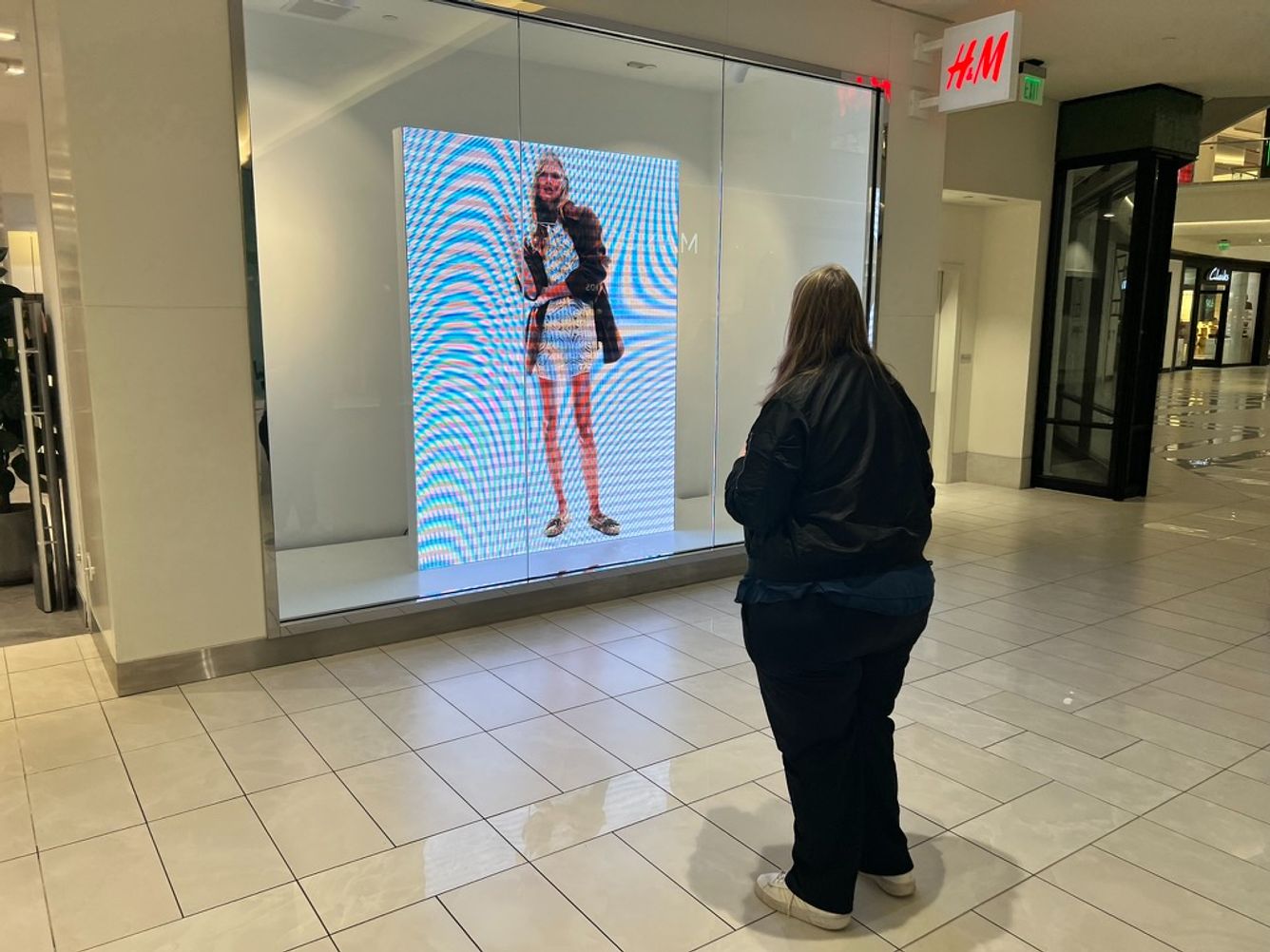 Kara Richardson Whitely observes a video with a thin model in a display window at an H&M in the American Dream Mall in New Jersey. 