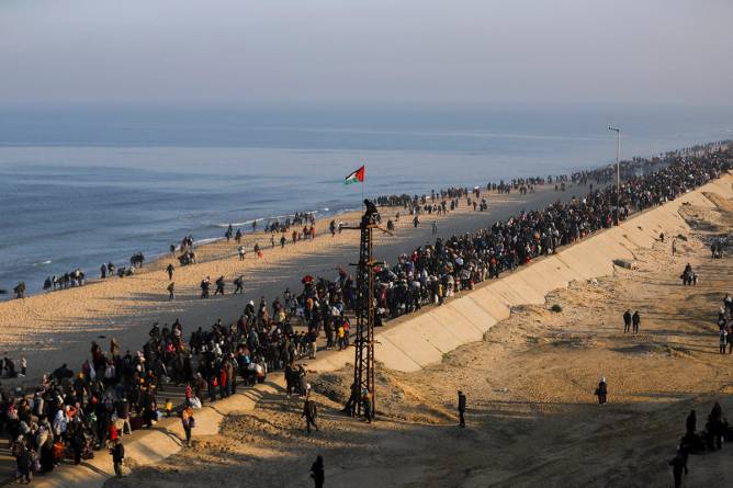 People walk along Gaza's Al-Rashid coastal street to cross the Netzarim Corridor from the southern Gaza Strip to the north on January 27, 2025