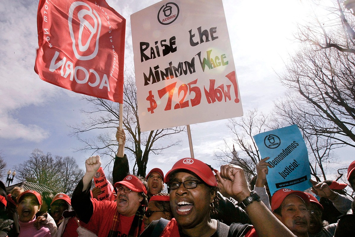 A group of protesters holding signs, shouting, with raised fists.