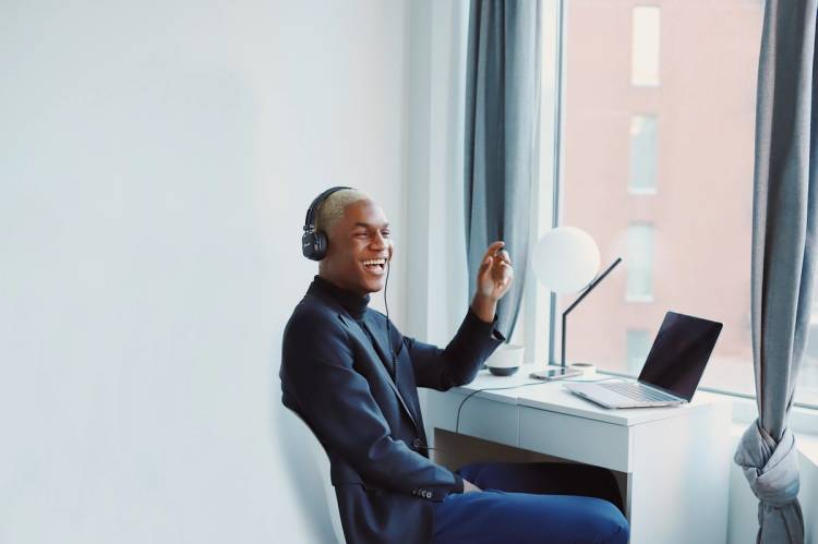 A person laughing while sitting at a desk with their laptop.