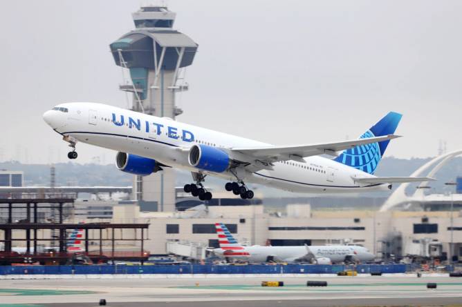 A United Airlines flight takes off on the runway in front of an air-traffic controller.