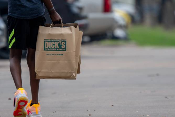 A customer carrying shopping bags exits a Dick's Sporting Goods.