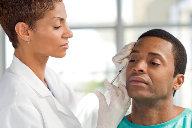 A female doctor administers Botox to a male patient.