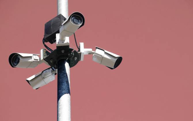 Image of a white security camera against a pink backdrop.