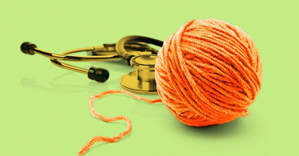 An orange ball of yarn unwinding next to a golden stethoscope