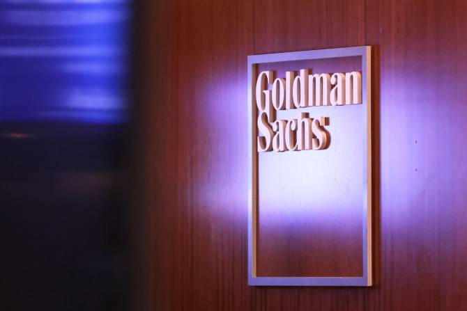 Goldman Sachs logo is pictured in a box on a brown wall.