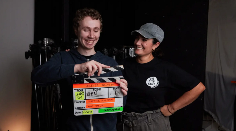 a person holding a clapperboard with a woman standing next to them smiling
