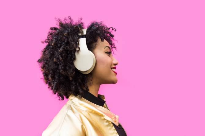 fashionable woman with headphones on pink background