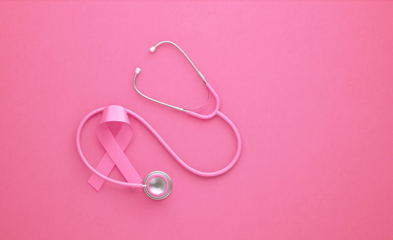 Pink breast cancer ribbon and a stethoscope on a pink background