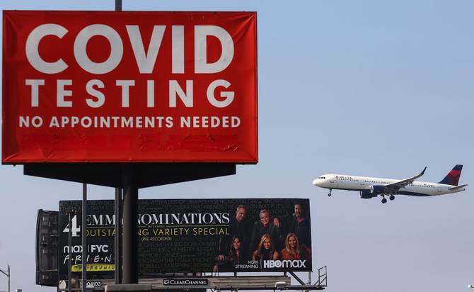 A Delta Air Lines plane lands near a COVID-19 testing sign at Los Angeles International Airport