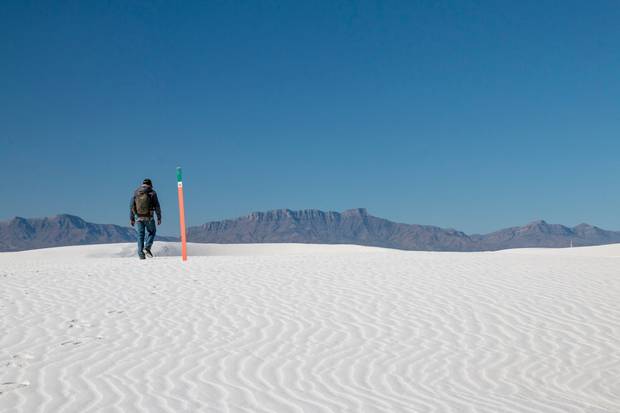 Bright orange trail markers guide visitors through the dunes of White Sands. 