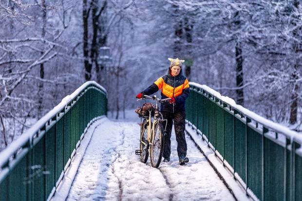 A person walks with his bicycle on a snow-covered bridge in Heerlen, southern Netherlands on January 9, 2025. 