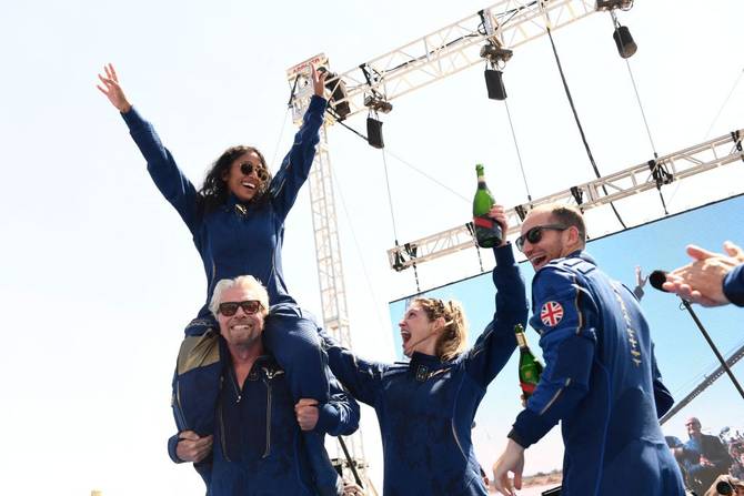 Sirisha Bandla sits on Richard Branson’s shoulders with fellow astronauts Beth Moses and Colin Bennett
