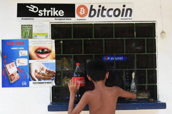 Salvadoran boy makes a purchase at a stall lined with bitcoin ads