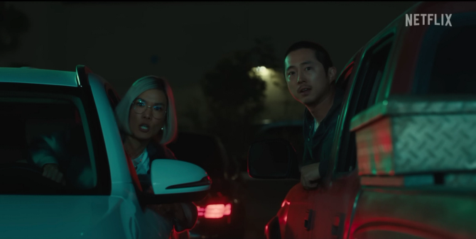 an image of Ali Wong and Steven Yeun as Amy Lau and Danny Cho leaning out of two cars at night in the Netflix original series Beef. 