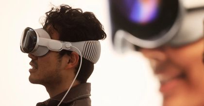 A man and woman wearing and using Apple Vision Pro VR headsets