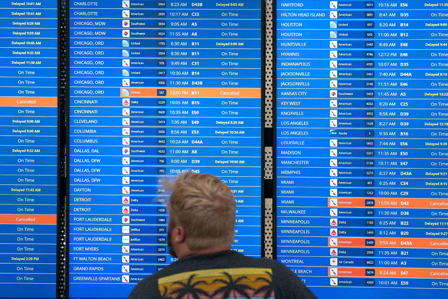 A traveler checks flight information showing cancelled and delayed status updates.