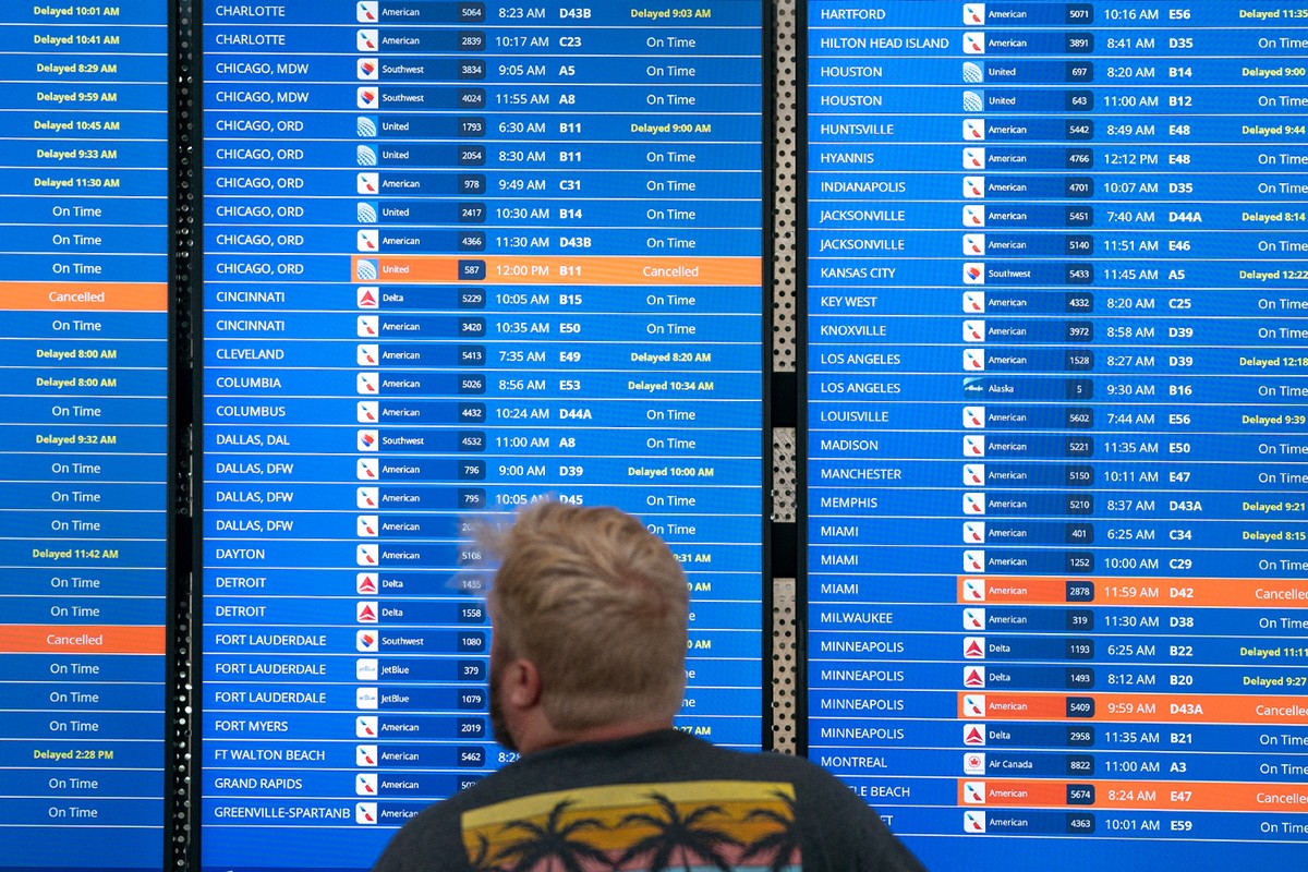 A traveler checks flight information showing cancelled and delayed status updates.